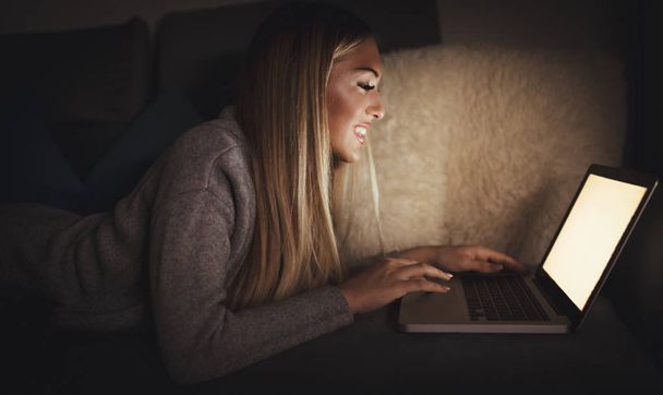 jovem mulher sorridente relaxante na cama e rede de surf no laptop
 - Foto, Imagem
