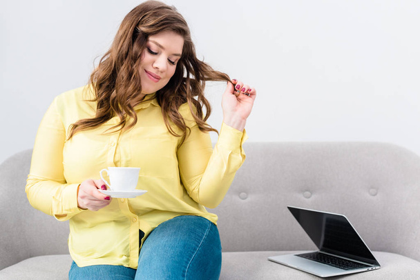 portrait of woman with cup of coffee sitting on sofa with laptop at home - Foto, imagen