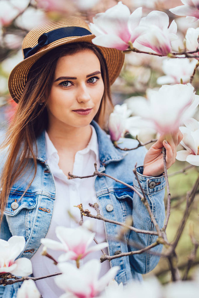 Hermosa chica de primavera en el sombrero de verano cerca de la floración del árbol de primavera con flores
 - Foto, Imagen