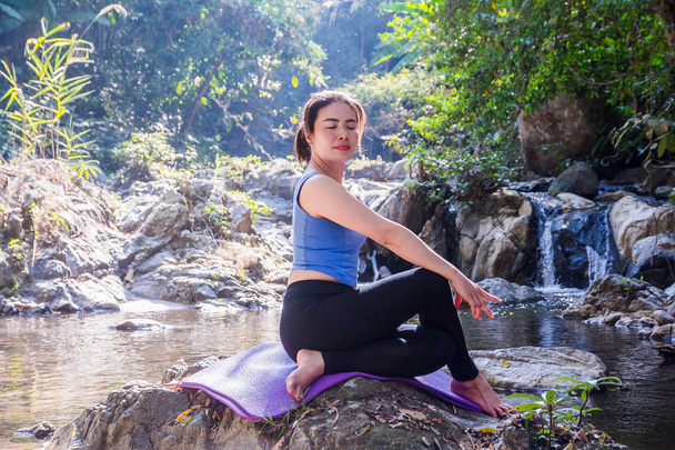 Vrouw mediteren doet yoga op een rivier rots. - Foto, afbeelding