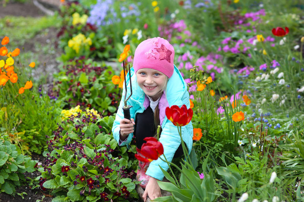Sweet girl takes care of the flowers in the garden - Valokuva, kuva