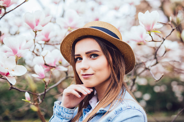 Feliz hermosa mujer joven en el parque de flores de primavera con magnolia árboles
. - Foto, Imagen