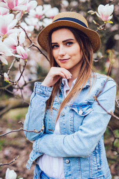 Portret van de jonge vrouw die lacht in de bloementuin in de de lentetijd. Amandel bloemen bloesems. - Foto, afbeelding