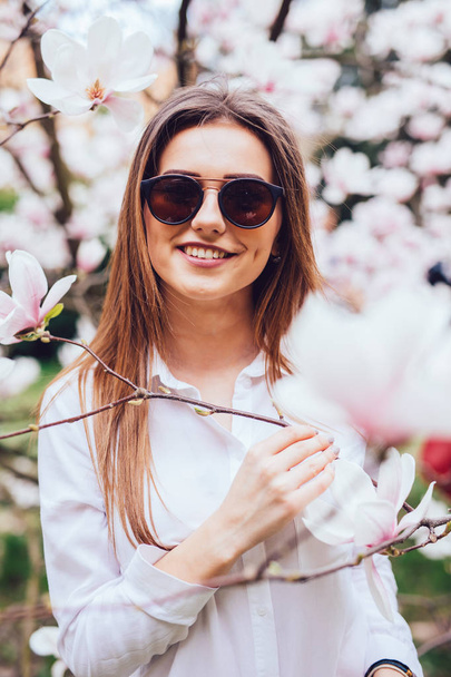 Portrait of Pretty spring woman in the garden with blossom magnolia flower trees - Фото, изображение