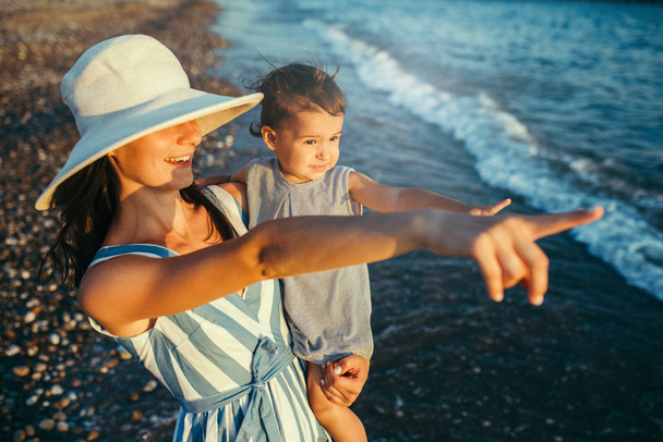 Beautiful mother hug daughter on the sea and beach background. H - Фото, изображение