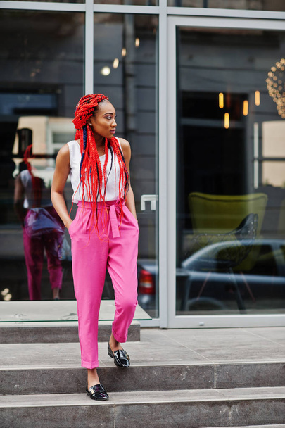 Fashionable african american girl at pink pants and red dreads p - Foto, Bild