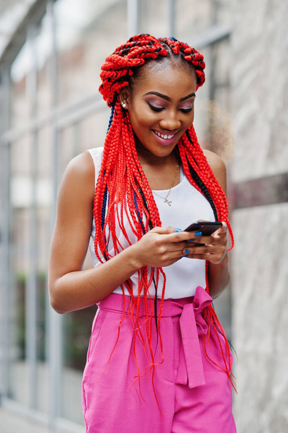 Fashionable african american girl at pink pants and red dreads p - Φωτογραφία, εικόνα