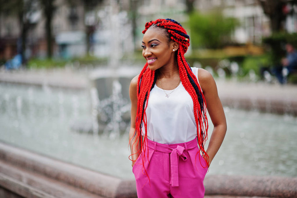 Fashionable african american girl at pink pants and red dreads p - 写真・画像