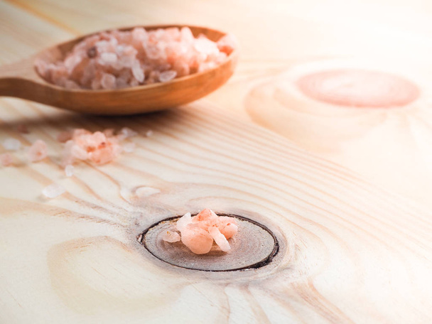 Large pink himalayan salt and wooden spoon on wooden table. - Photo, image