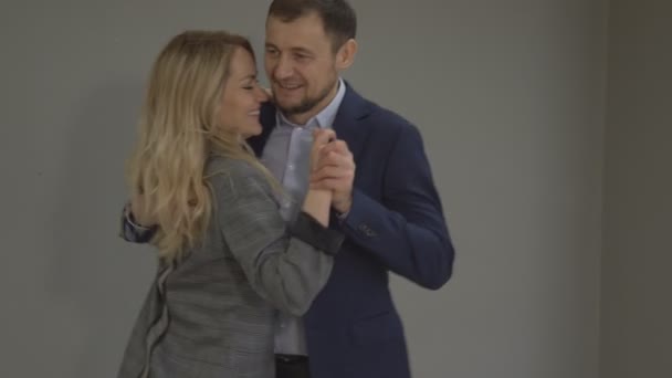 Mann und Frau tanzen im Büro auf dem grauen Untergrund einen langsamen Tanz. - Filmmaterial, Video
