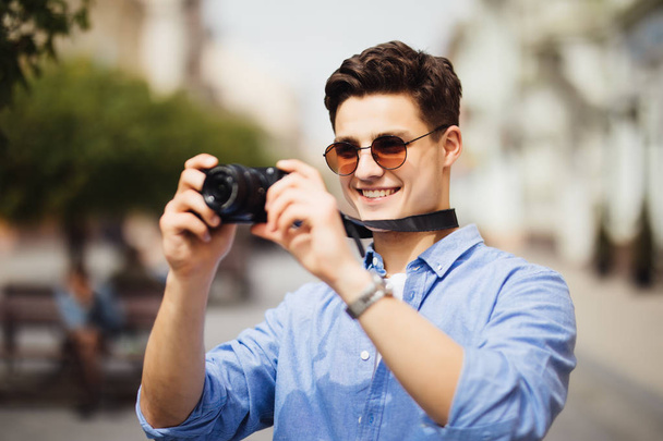 観光通りの写真を撮るカメラの男。カメラを持って、旧市街を歩きながら興味深い場所の写真を作るハンサムな笑顔の男性の肖像画. - 写真・画像