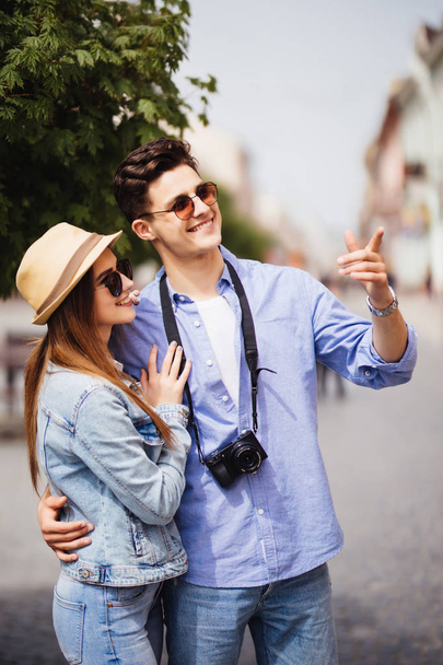 Giovane coppia di turisti che fanno una passeggiata in un marciapiede di strada della città in una giornata di sole
 - Foto, immagini