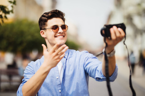 Un bel turista che si fa un selfie a vocazione. Giovanotto che sorride alla telecamera in una scena urbana. Popolo caucasico. Concetto di persone, stile di vita e tecnologia
 - Foto, immagini