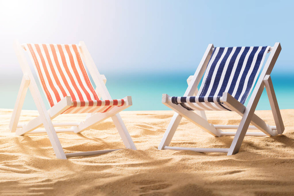 Close-up Of Two Blue And Red Striped Deck Chairs On Sandy Beach - 写真・画像