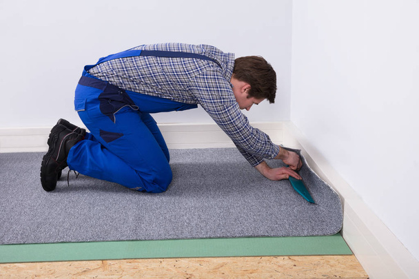 Side View Of A Male Worker Fitting Grey Carpet On Floor - Fotoğraf, Görsel