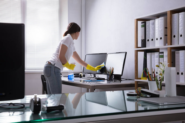 Young Woman Cleaning Computer With Rag In Office - Fotoğraf, Görsel