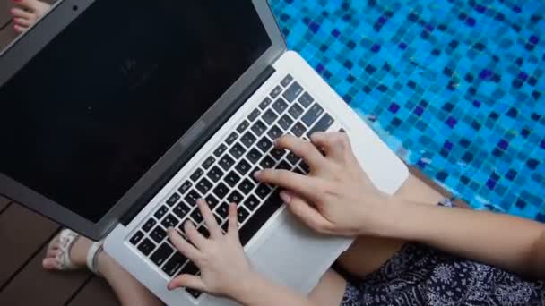 Close-up van typewriting op laptop toetsenbord in de buurt van blauwe zwembad. - Video