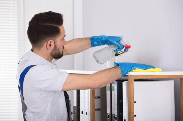 Close-up Of A Young Male Cleaner Cleaning Shelf At Workplace - Φωτογραφία, εικόνα