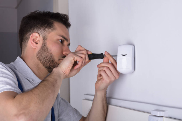 Close-up Of A Young Male Electrician Installing Security System Door Sensor On Wall - Fotografie, Obrázek