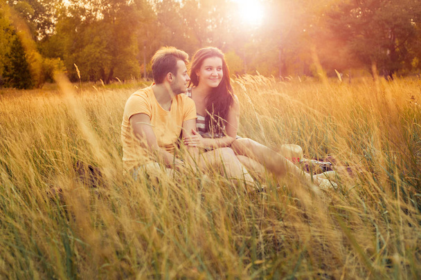 loving couple sitting on floral field in autumnal park at warm sunny day, happiness and love concept - Fotografie, Obrázek
