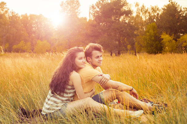 loving couple sitting on floral field in autumnal park at warm sunny day, happiness and love concept - Photo, Image