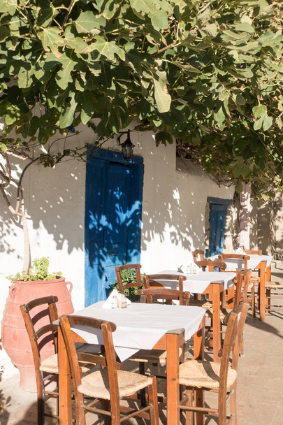 Tische und Stühle im Freien unter einem Baum, Heraklion, Griechenland - Foto, Bild