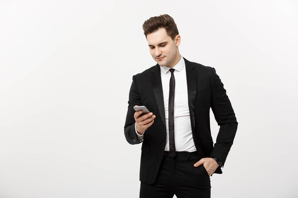 Concept d'entreprise : Heureux jeune homme d'affaires en costume intelligent dactylographie sms sur fond gris
 - Photo, image