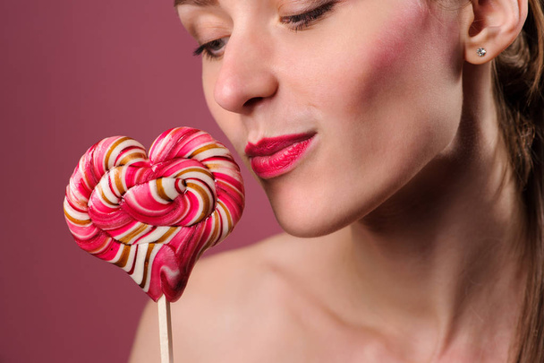 emotional sexy girl with a lollipop over pink background in studio - Fotoğraf, Görsel