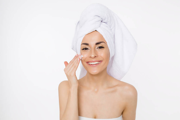 Face cream. Skin care. Beautiful smiling woman with a towel on her head after showering. Cosmetology. Beauty & Spa - Φωτογραφία, εικόνα