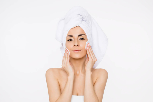 Removing makeup. Beauty and spa. A beautiful smiling woman with a towel on her head moisturizes or cleanses her face from makeup using cotton pads. Cosmetology. Women Health - Foto, Bild