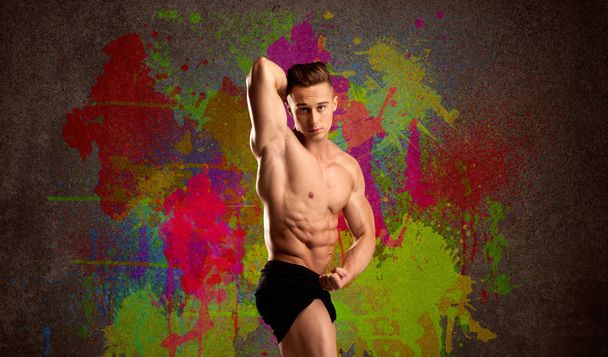 Strong guy with colorful paint wall and weight - Foto, Bild