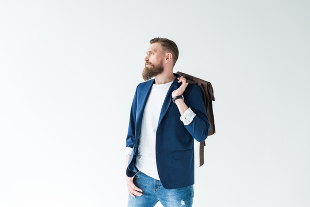schöner Mann in lässiger Kleidung mit Rucksack, der isoliert auf hellem Hintergrund wegschaut - Foto, Bild