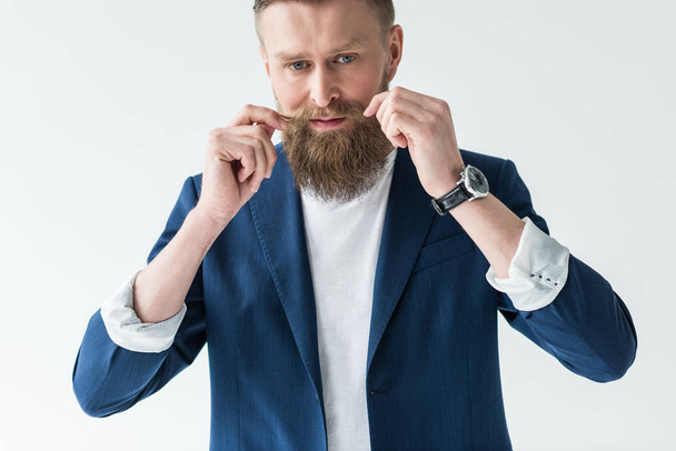 Handsome bearded man styling his mustache isolated on light background - Foto, Imagem