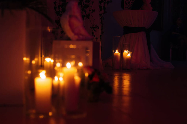 vysoké svíčky ve skleněných baněk v temné místnosti. Kulatý stůl s  - Fotografie, Obrázek