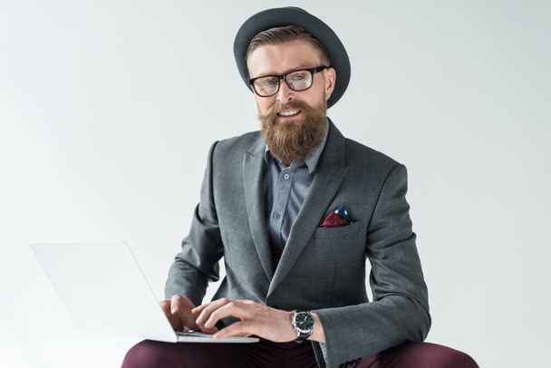 Knappe zakenman in vintage stijl kleding bezig met laptop geïsoleerd op lichte achtergrond - Foto, afbeelding