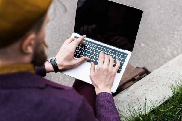 Zbliżenie człowiek siedzący na ulicy i wpisując na klawiaturze laptopa - Zdjęcie, obraz