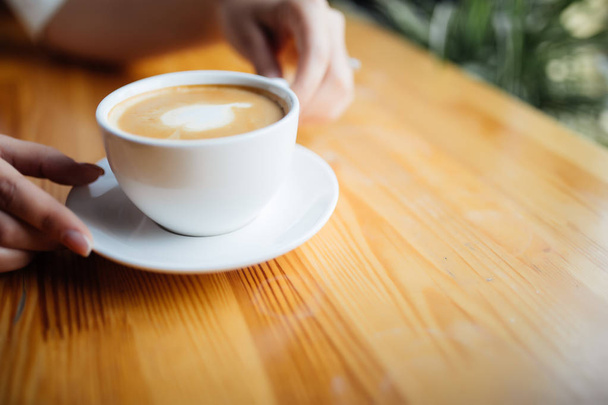 Gros plan des mains féminines tenant une tasse de café à la cafétéria
 - Photo, image