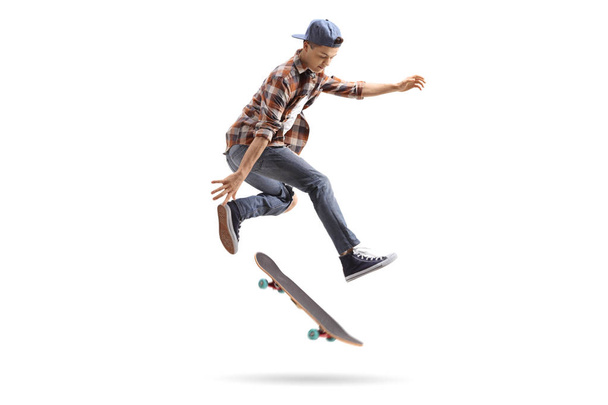 Teenage skater performing a trick with a skateboard isolated on white background - Photo, image