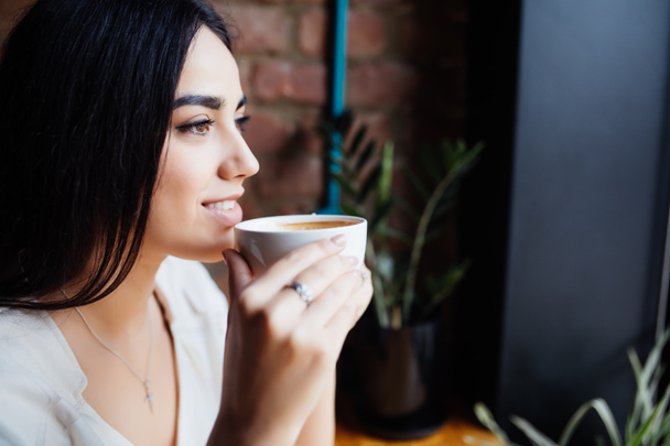 Кофе. Красивая девушка пьет чай или кофе в кафе. Красотка-модель с чашкой горячего напитка
. - Фото, изображение