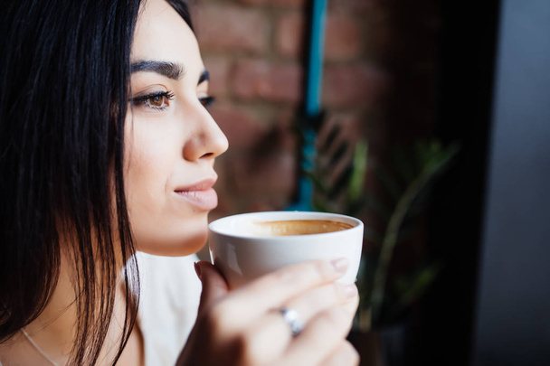 Портрет красивої жінки, що п'є каву в сучасному кафе
 - Фото, зображення