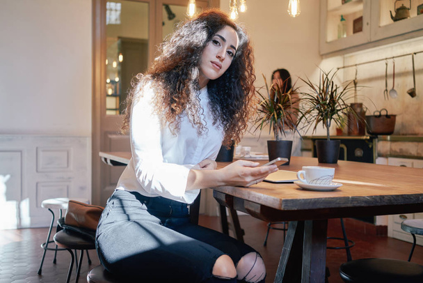 young attractive woman using smartphone in a cafe during the lunch break - Фото, изображение