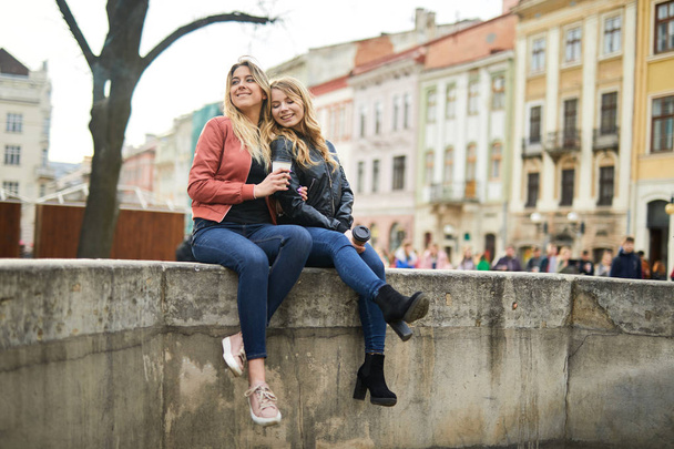 Two girls sit on the fountain and talk to each other  - Foto, Imagen