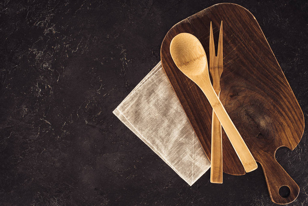 vista superior de la cuchara, tenedor para la carne en la tabla de cortar de madera y el saco
 - Foto, imagen