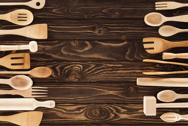 elevated view of kitchen utensils placed in two rows on wooden table - Foto, afbeelding
