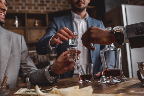 cropped shot of multiethnic men drinking alcohol together - Foto, imagen