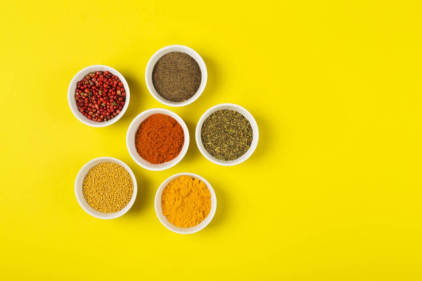 Various spices in bowls on yellow background. Top view, copy spa - Fotoğraf, Görsel