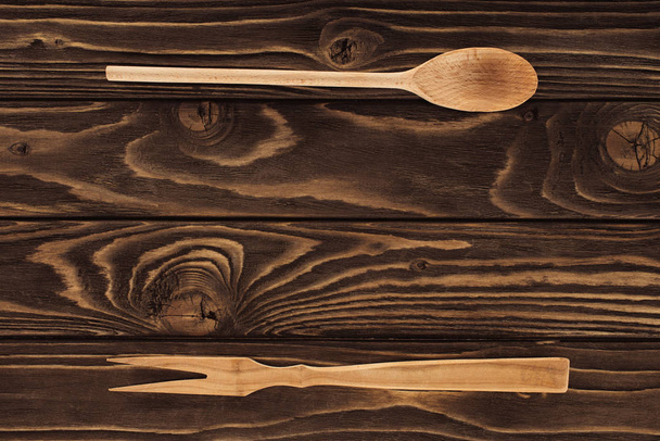 vista sopraelevata della forchetta in legno per carne e cucchiaio sul tavolo
  - Foto, immagini