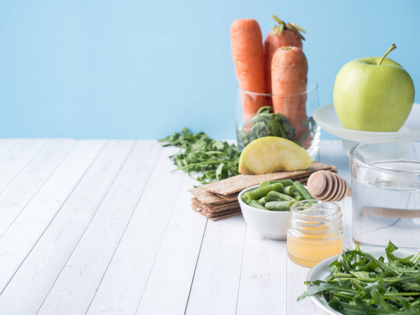 Healthy diet food on the table Arugula Green Beans Apple Water Honey Cracker Carrot Copy space - Foto, imagen