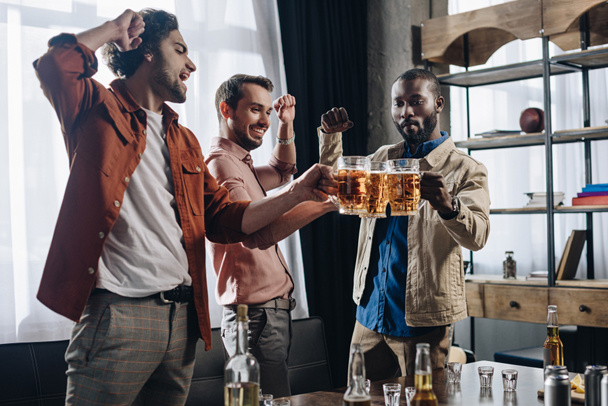 возбужденные друзья-мужчины звонят в пивные бокалы во время вечеринки вместе
 - Фото, изображение