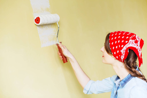 Hermosa chica en rojo Diadema pintura de la pared con rollo de pintura
 - Foto, imagen